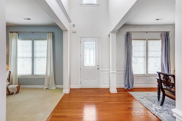 foyer entrance with a healthy amount of sunlight, decorative columns, visible vents, and crown molding