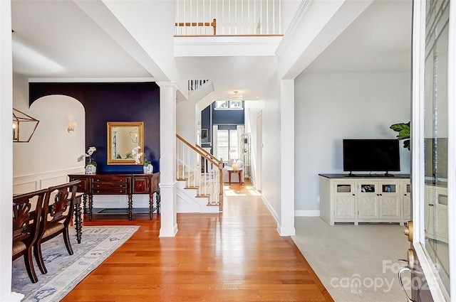 foyer featuring light wood-style floors, wainscoting, ornamental molding, and stairway