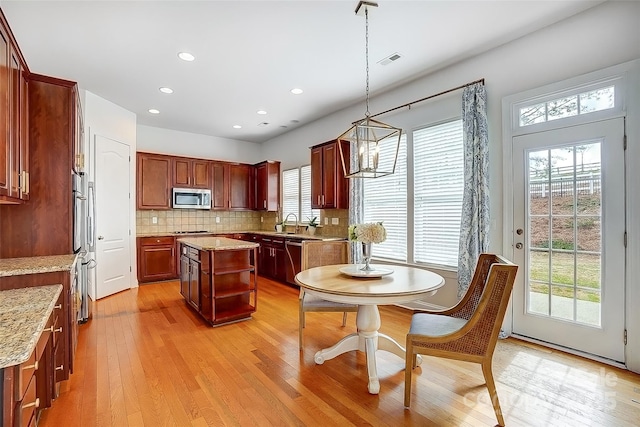 kitchen featuring visible vents, decorative backsplash, appliances with stainless steel finishes, hanging light fixtures, and light wood-style floors