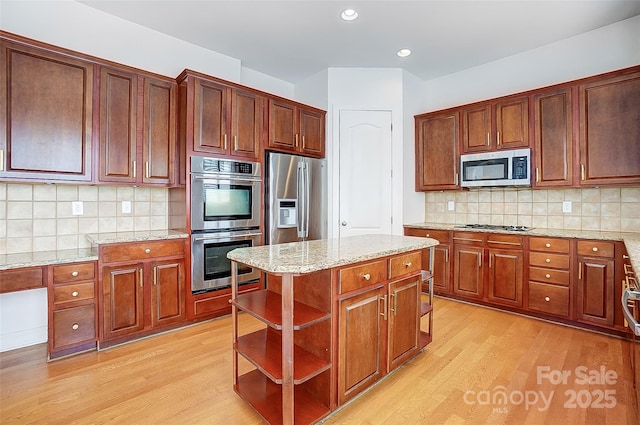 kitchen with appliances with stainless steel finishes, light wood-style flooring, light stone counters, and open shelves