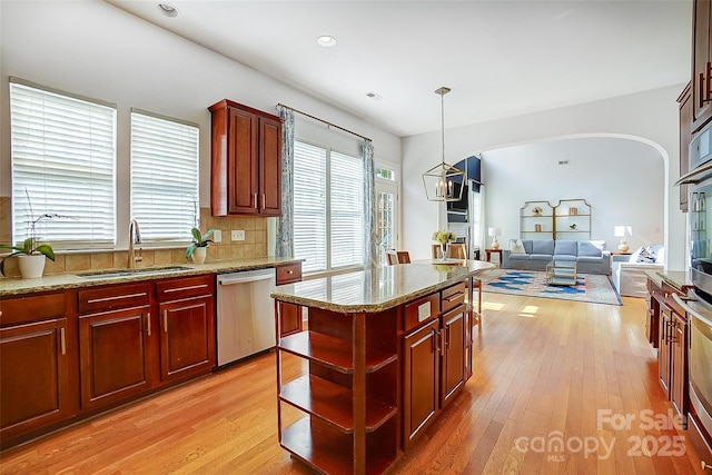 kitchen featuring a sink, light wood-style floors, open shelves, and stainless steel dishwasher