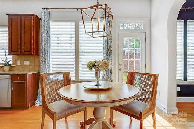 dining area with arched walkways, an inviting chandelier, light wood-style flooring, and baseboards