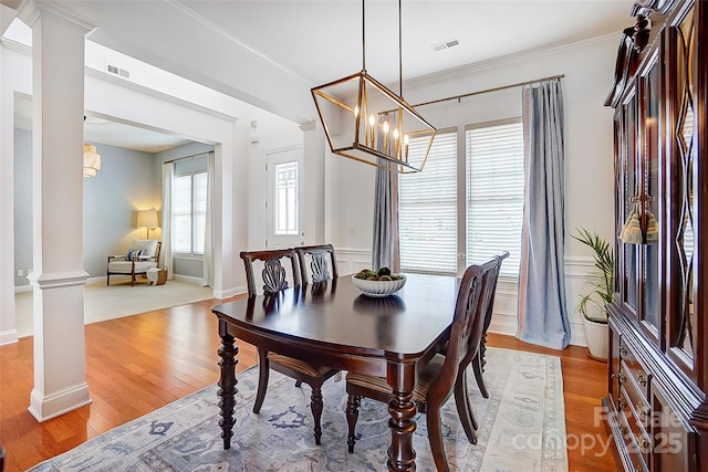 dining room featuring ornate columns, light wood-style flooring, visible vents, and crown molding