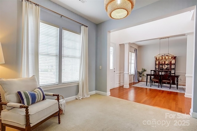 living area featuring plenty of natural light, decorative columns, carpet, and wood finished floors