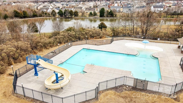 pool featuring a water slide, a water view, fence, and a residential view