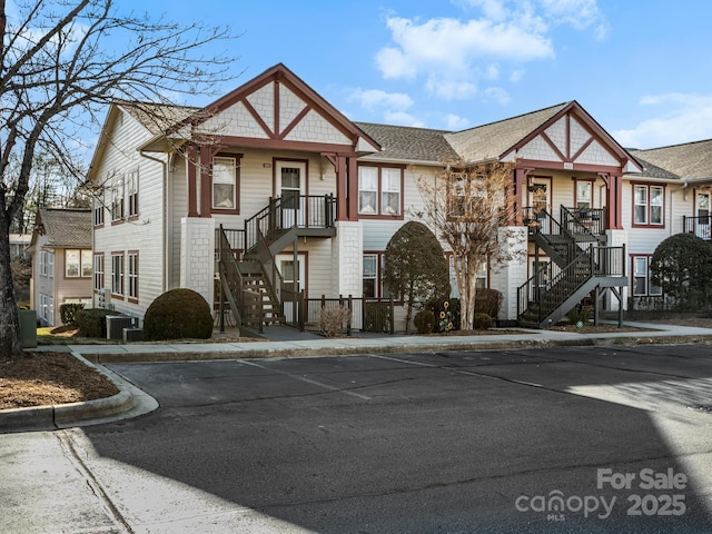 view of front of home featuring uncovered parking, central AC, and stairway