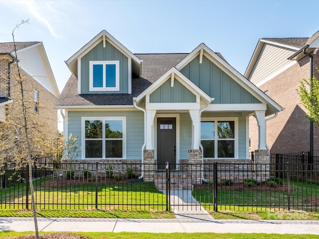 view of front of property with board and batten siding, a fenced front yard, a front yard, a porch, and a shingled roof