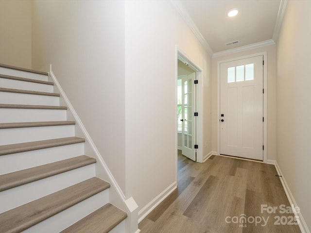 foyer entrance featuring baseboards, recessed lighting, stairway, crown molding, and wood finished floors