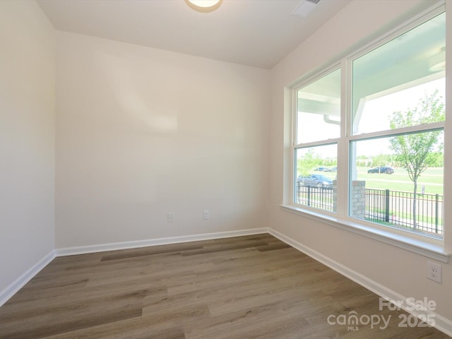 unfurnished room with visible vents, baseboards, and wood finished floors