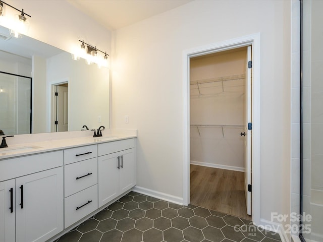 full bath with a sink, a spacious closet, tile patterned floors, and a shower stall