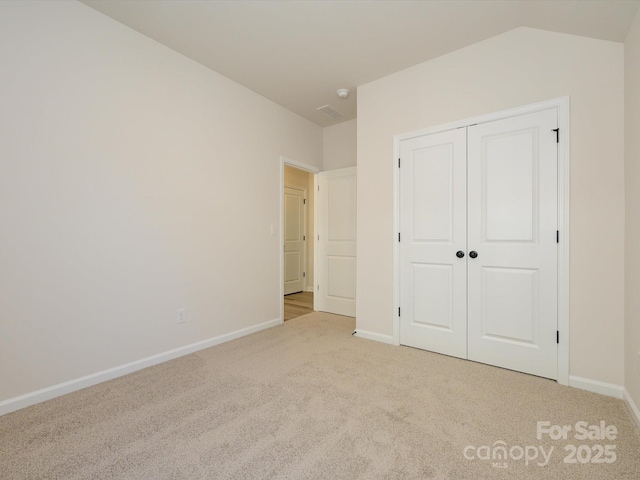 unfurnished bedroom with a closet, baseboards, and light carpet