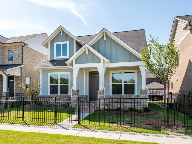 craftsman-style house featuring a porch, board and batten siding, a shingled roof, and a front yard