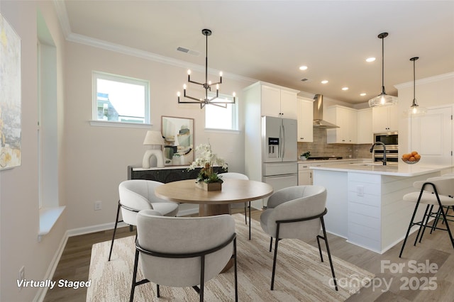 17025 Malone Ln, Mint Hill, NC 28227 - kitchen with stainless steel appliances, wall chimney exhaust hood, a sink, light wood finished floors, and ornamental molding