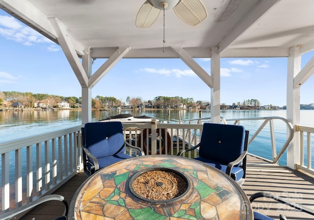 wooden terrace with a water view and ceiling fan