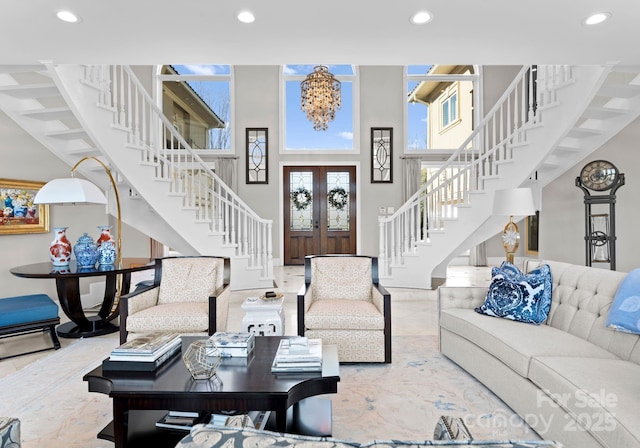 living room with a towering ceiling, recessed lighting, stairs, and french doors