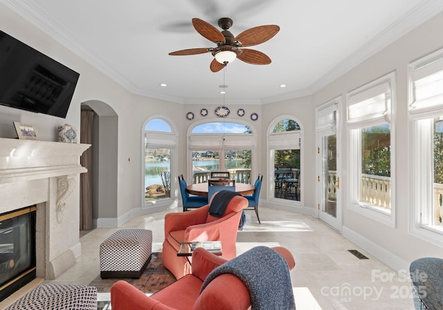 sunroom / solarium featuring arched walkways, a water view, visible vents, a premium fireplace, and a ceiling fan