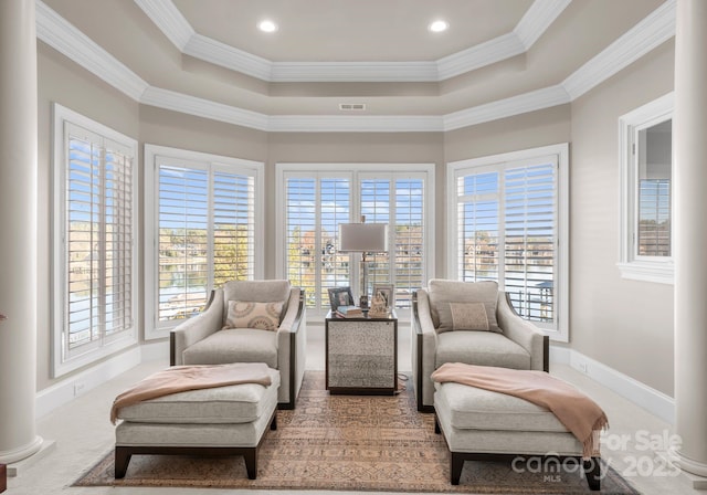 living area with visible vents, baseboards, a raised ceiling, and crown molding