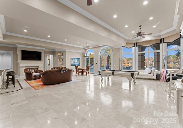 living area with a fireplace, a raised ceiling, a ceiling fan, and recessed lighting