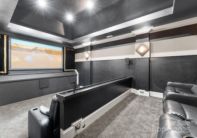 carpeted cinema room with a tray ceiling and a decorative wall