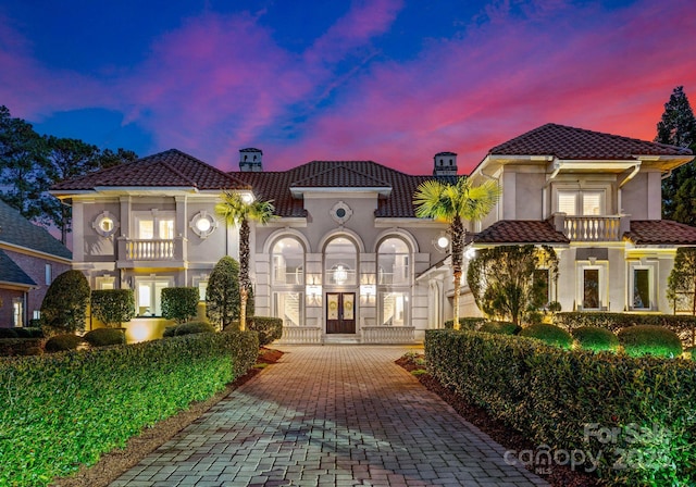 view of front of house featuring a tiled roof, french doors, a balcony, and stucco siding