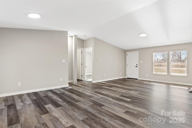 unfurnished living room featuring baseboards and dark wood finished floors