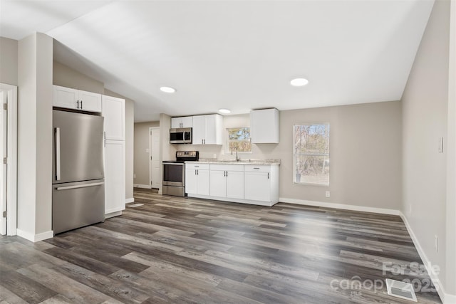 kitchen with stainless steel appliances, dark wood-style flooring, a sink, and white cabinets