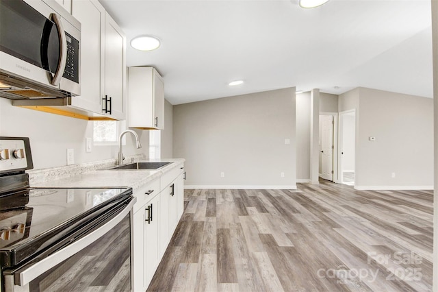 kitchen featuring stainless steel appliances, a sink, white cabinets, light countertops, and light wood finished floors