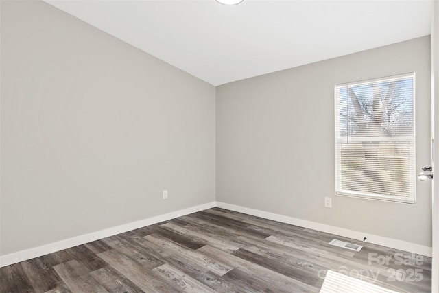 unfurnished room featuring dark wood-style floors, visible vents, and baseboards