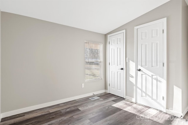 interior space with dark wood-style floors, lofted ceiling, a closet, and baseboards