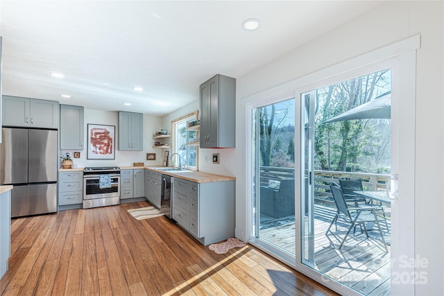 kitchen with gray cabinets, appliances with stainless steel finishes, sink, and light hardwood / wood-style flooring