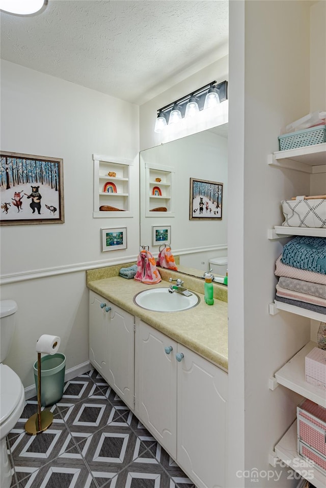 bathroom featuring vanity, toilet, and a textured ceiling