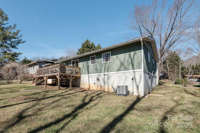 rear view of house featuring a wooden deck, cooling unit, and a lawn