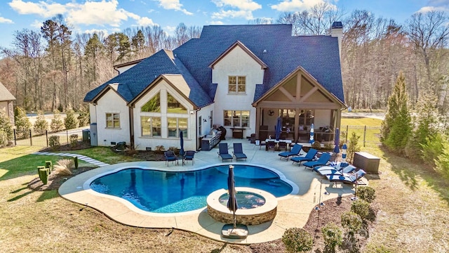 rear view of property with a swimming pool with hot tub and a patio area