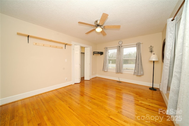 unfurnished room featuring a textured ceiling, baseboards, light wood finished floors, and ceiling fan