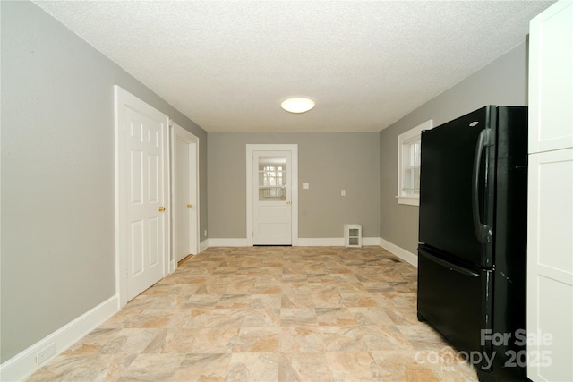 kitchen with visible vents, baseboards, a textured ceiling, and freestanding refrigerator