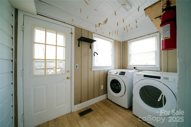 laundry room with baseboards, visible vents, laundry area, light wood-type flooring, and washer and clothes dryer