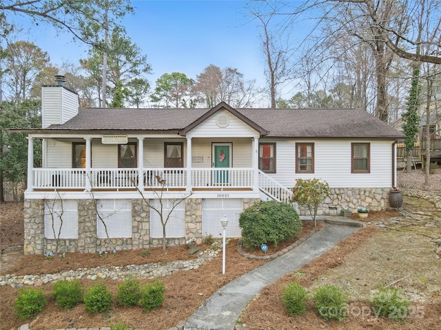 ranch-style home with roof with shingles, covered porch, and a chimney