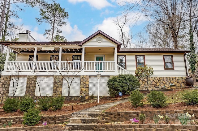 ranch-style house featuring stairway, covered porch, and a chimney