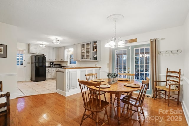 dining space featuring light wood-style flooring, baseboards, and a chandelier