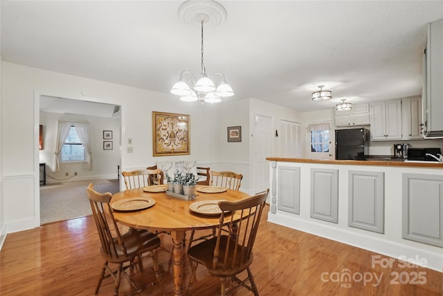 dining room with baseboards, light wood-style floors, and an inviting chandelier