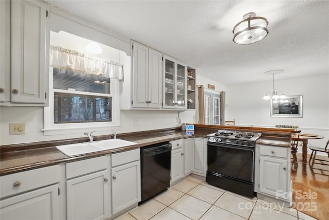 kitchen featuring dishwasher, dark countertops, gas range oven, and a sink