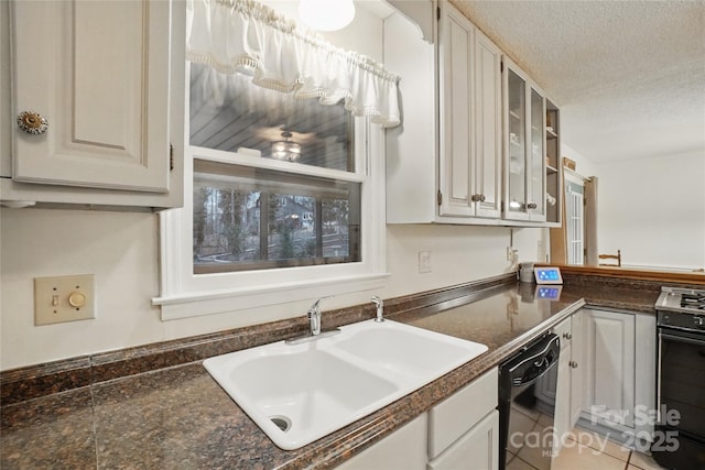 kitchen with dark countertops, black appliances, light tile patterned flooring, a textured ceiling, and a sink