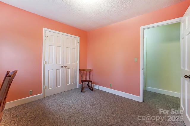 unfurnished bedroom featuring baseboards, carpet floors, a textured ceiling, and a closet