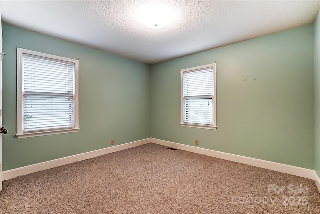 carpeted empty room featuring visible vents, baseboards, and a textured ceiling