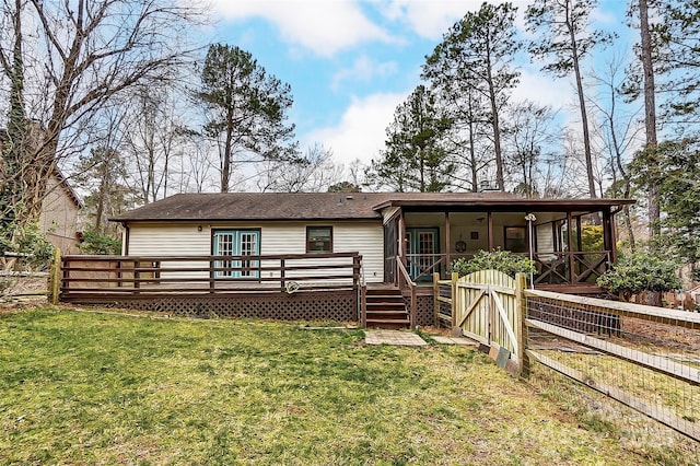 rear view of property with a wooden deck and a lawn