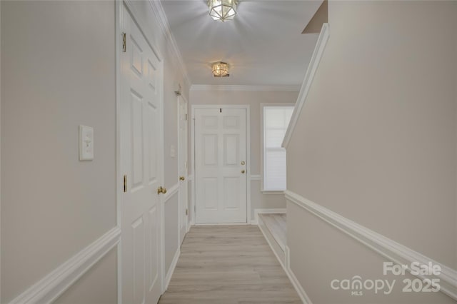 hallway with ornamental molding, light wood-style flooring, and baseboards