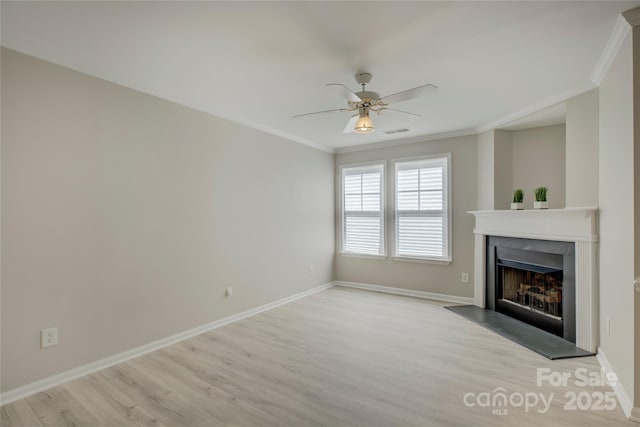 unfurnished living room with ornamental molding, visible vents, a fireplace with raised hearth, and baseboards