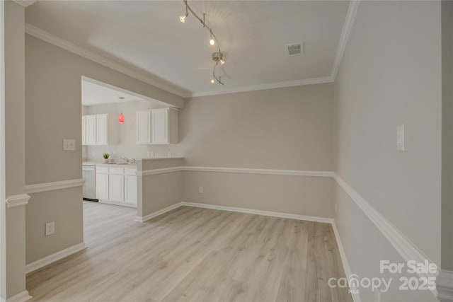 empty room featuring baseboards, visible vents, crown molding, and light wood finished floors