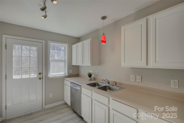 kitchen featuring a sink, white cabinetry, light countertops, stainless steel dishwasher, and decorative light fixtures