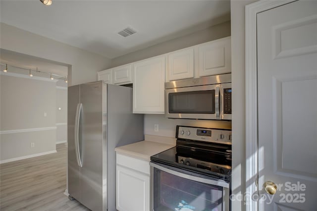 kitchen featuring stainless steel appliances, visible vents, white cabinetry, light countertops, and light wood finished floors